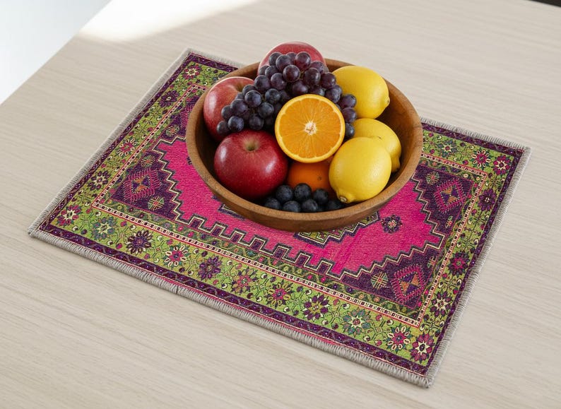 A wooden bowl filled with various fruits, including apples, oranges, and grapes, sits on a colorful, patterned placemat on a wooden table.