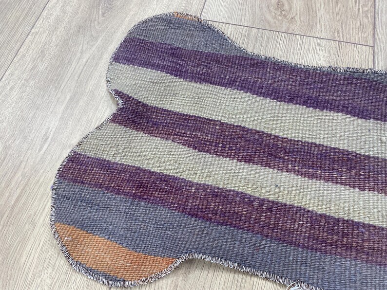 Handmade colorful Turkish Kilim pet mats, boho upcycled rug designed for pets, unique bone-shaped feeding mat, durable woven fabric, eco-friendly recycled carpet, decorative home accent, vibrant patterns and textures, comfortable and easy-to-clean, perfect for indoor or outdoor use, adds charm to any pet feeding area, ideal gift for pet lovers, artisanal inspired Turkish weave, stylish addition to pet space, one-of-a-kind handmade design.