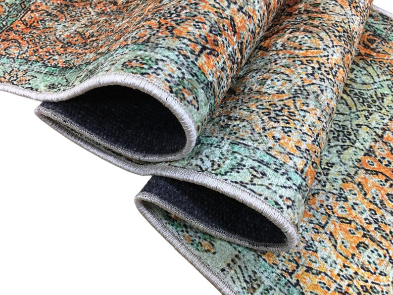 a close-up view of a colorful, patterned rug with a mix of orange, green, and black colors. The rug appears to be made of a soft, plush material and has a textured surface.