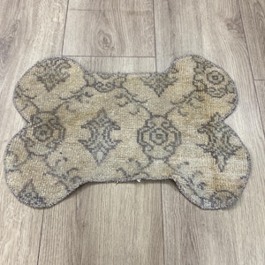 Handmade colorful Turkish Kilim pet mats, boho upcycled rug designed for pets, unique bone-shaped feeding mat, durable woven fabric, eco-friendly recycled carpet, decorative home accent, vibrant patterns and textures, comfortable and easy-to-clean, perfect for indoor or outdoor use, adds charm to any pet feeding area, ideal gift for pet lovers, artisanal inspired Turkish weave, stylish addition to pet space, one-of-a-kind handmade design.