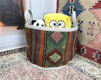 May include: A colourful woven storage basket with a white rim, filled with stuffed toys, including a yellow sponge character and a black and white panda.