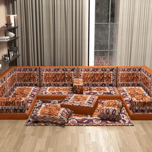 May include: A large, modular sectional sofa with a vibrant, patterned design in shades of orange, brown, and purple. The sofa includes multiple seating sections, cushions, and a matching ottoman, creating a cosy and inviting living space.