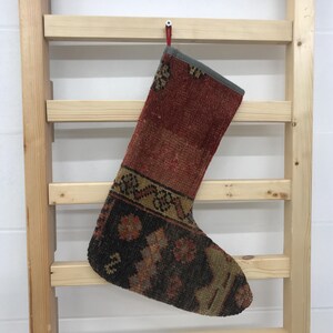 May include: A red, brown, and black patterned Christmas stocking made from a woven rug.