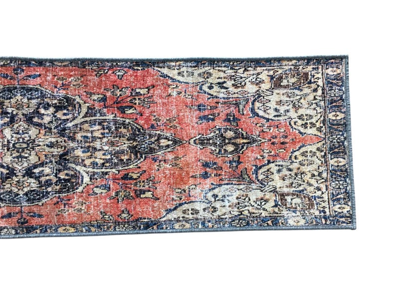 a vibrant, intricately patterned rug with a mix of red, blue, and white colors. The rug has a geometric design with floral and abstract elements, creating a visually striking and textured appearance.