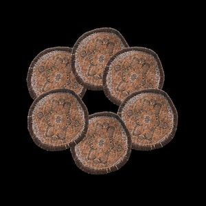 May include: Six round coasters with a brown and tan patterned design. Each coaster has a dark brown border and a lighter tan fringe. The coasters are arranged in a circular pattern against a black background.
