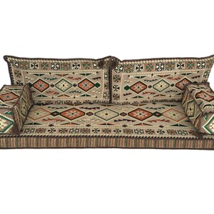 May include: A brown and beige floor cushion with a geometric pattern. The cushion is made up of three sections, two backrests and a main seating area. The cushion is perfect for sitting on the floor.