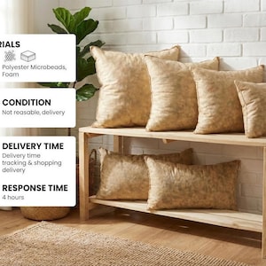 May include: A collection of six beige throw pillows with a subtle mottled texture, arranged on a two-tiered light wood bench. The set includes four square pillows and two rectangular pillows, all featuring a soft, neutral-toned fabric finish.