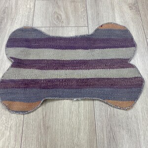 Handmade colorful Turkish Kilim pet mats, boho upcycled rug designed for pets, unique bone-shaped feeding mat, durable woven fabric, eco-friendly recycled carpet, decorative home accent, vibrant patterns and textures, comfortable and easy-to-clean, perfect for indoor or outdoor use, adds charm to any pet feeding area, ideal gift for pet lovers, artisanal inspired Turkish weave, stylish addition to pet space, one-of-a-kind handmade design.