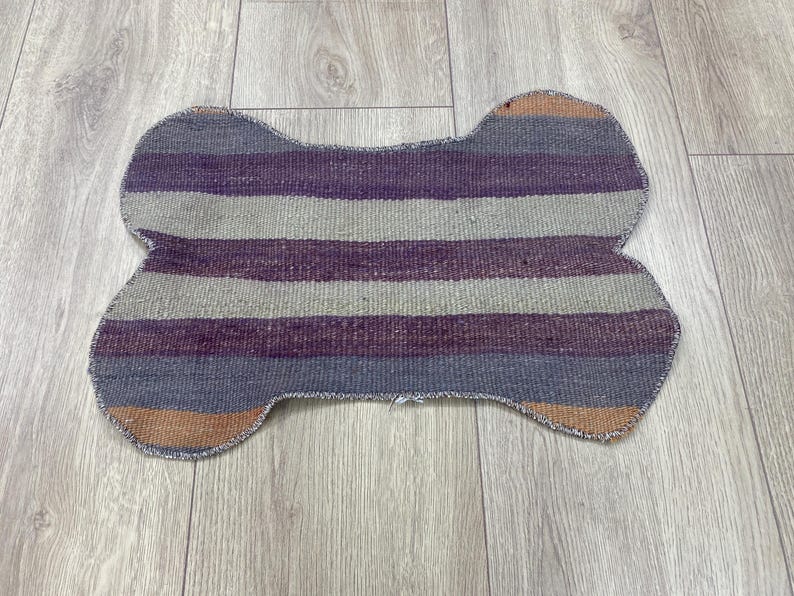 Handmade colorful Turkish Kilim pet mats, boho upcycled rug designed for pets, unique bone-shaped feeding mat, durable woven fabric, eco-friendly recycled carpet, decorative home accent, vibrant patterns and textures, comfortable and easy-to-clean, perfect for indoor or outdoor use, adds charm to any pet feeding area, ideal gift for pet lovers, artisanal inspired Turkish weave, stylish addition to pet space, one-of-a-kind handmade design.