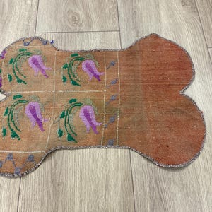 Handmade colorful Turkish Kilim pet mats, boho upcycled rug designed for pets, unique bone-shaped feeding mat, durable woven fabric, eco-friendly recycled carpet, decorative home accent, vibrant patterns and textures, comfortable and easy-to-clean, perfect for indoor or outdoor use, adds charm to any pet feeding area, ideal gift for pet lovers, artisanal inspired Turkish weave, stylish addition to pet space, one-of-a-kind handmade design.