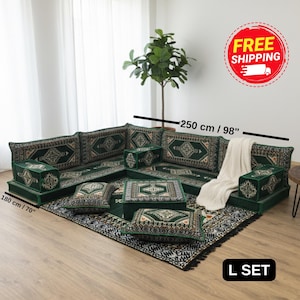 May include: An L-shaped floor sofa set in dark green with intricate geometric patterns, including backrests, armrests, and two floor cushions. The set measures 250 cm by 180 cm, or 98 inches by 70 inches. A white throw blanket is draped over the sofa.