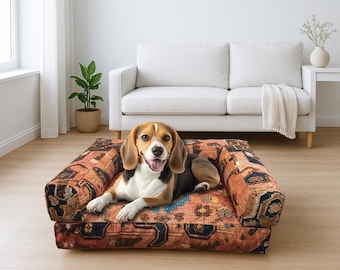 May include: A beagle dog rests on a patterned dog bed with armrests. The bed features a warm color palette of orange, brown, and blue. The dog is brown, black, and white, with its tongue out.