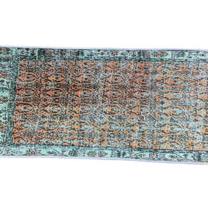 a colorful, patterned rug with a geometric design in shades of green, orange, and blue.