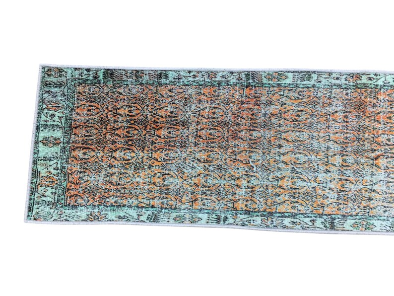 a colorful, patterned rug with a geometric design in shades of green, orange, and blue.
