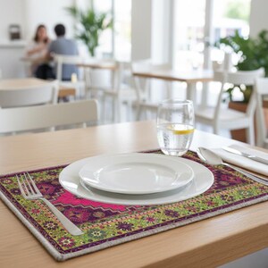 A table setting with a white plate, silverware, and a glass of water, placed on a colorful placemat in a restaurant setting.