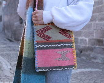 Può includere: Una borsa tote tessuta colorata con un motivo geometrico in tonalità di rosa, marrone, beige e giallo. La borsa ha un bordo con frange bianche e un bordo cucito giallo.