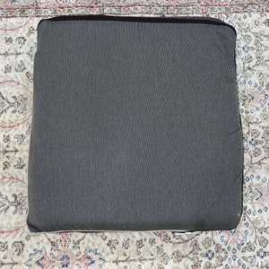 May include: A dark gray rectangular cushion with a smooth, textured surface.