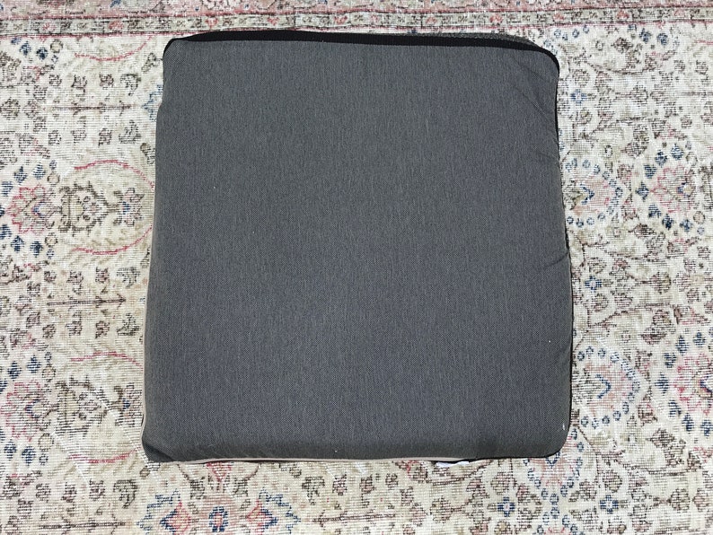 May include: A dark gray rectangular cushion with a smooth, textured surface.