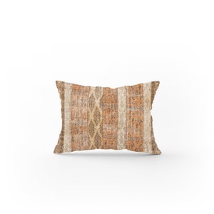 May include: A rectangular throw pillow with a beige and orange geometric pattern. The pillow has a faded, vintage look.
