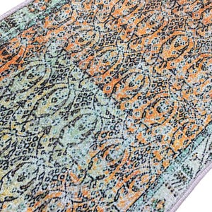 a close-up view of a colorful, patterned rug or carpet with a mix of orange, green, and black designs.