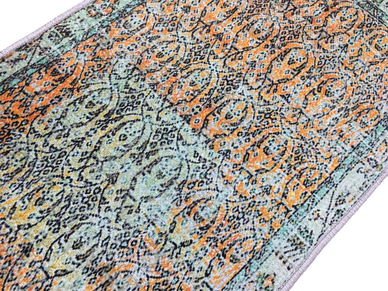 a close-up view of a colorful, patterned rug or carpet with a mix of orange, green, and black designs.