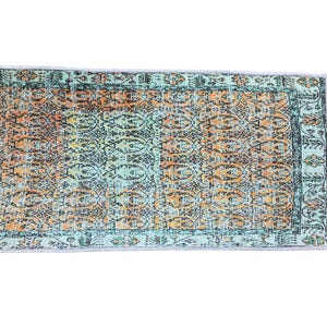 a colorful, patterned rug with a geometric design in shades of blue, orange, and green.