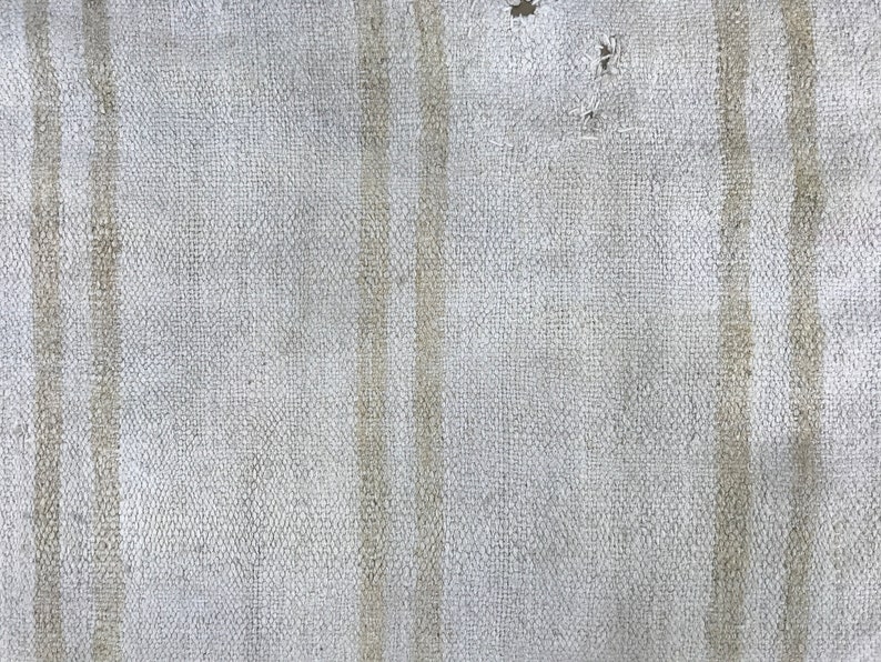 May include: Close-up of a white canvas texture with vertical lines. The canvas has a slightly rough texture and a subtle sheen.