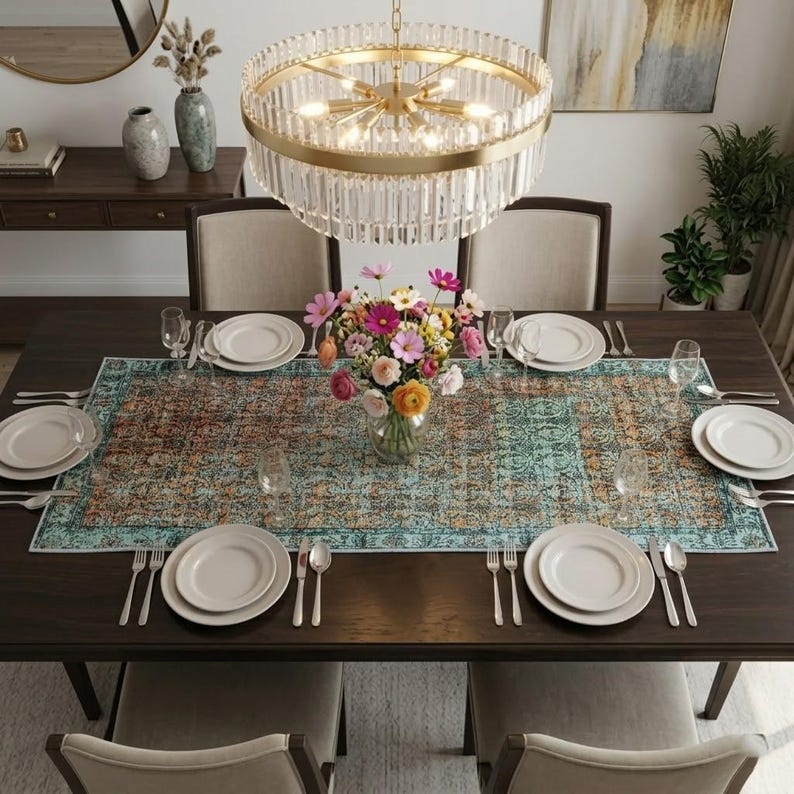 a dining room with a large wooden table set for four, featuring white plates, silverware, and a vase of colorful flowers. The table is surrounded by four chairs, and a chandelier hangs above it, casting a warm glow over the scene. The room is decorated with various vases, potted plants, and other decorative elements, creating a cozy and inviting atmosphere.