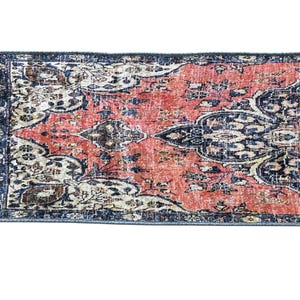 a vibrant, intricately patterned rug with a mix of red, blue, and white colors. The rug has a detailed design with floral and geometric patterns, creating a visually striking and eye-catching piece.