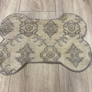 Handmade colorful Turkish Kilim pet mats, boho upcycled rug designed for pets, unique bone-shaped feeding mat, durable woven fabric, eco-friendly recycled carpet, decorative home accent, vibrant patterns and textures, comfortable and easy-to-clean, perfect for indoor or outdoor use, adds charm to any pet feeding area, ideal gift for pet lovers, artisanal inspired Turkish weave, stylish addition to pet space, one-of-a-kind handmade design.