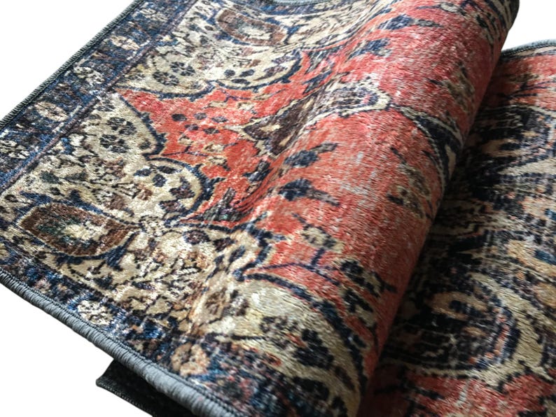 a close-up view of a vibrant, intricately patterned rug with a mix of red, blue, and beige colors. The rug appears to be a traditional or vintage design, with a detailed and ornate pattern that adds visual interest and complexity to the scene.