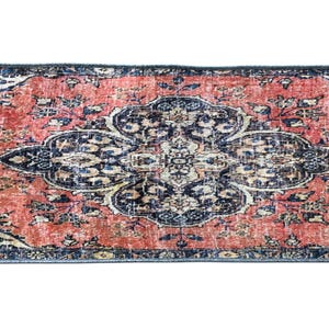 a vibrant, intricately patterned rug with a striking combination of red, blue, and white colors. The rug is adorned with a floral design and appears to be a piece of traditional or cultural art.