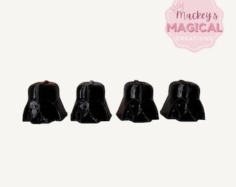 May include: Four black Darth Vader helmet cake toppers. The helmets are made of a smooth, black material and have a detailed design.