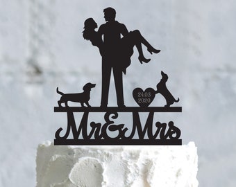 Op de afbeelding: Zwarte silhouet caketopper met een stel dat een hart vasthoudt met de datum 24.03.2020, twee honden en de tekst "Mr & Mrs".
