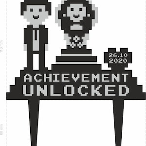 May include: Black and grey cake topper with pixelated figures and text. The topper features a man in a suit, a trophy, and the words "ACHIEVEMENT UNLOCKED" with the date "26.10 2020". The topper is 14.2 cm wide and 11 cm high.