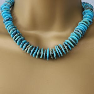 May include: A turquoise necklace made of round, flat beads. The beads are strung on a silver chain.