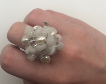 May include: A white ring with a cluster of white and clear stones and pearls.
