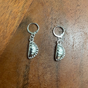 Peut inclure: Une paire de boucles d'oreilles en argent avec un charme texturé en forme de croissant qui ressemble à une pâtisserie.