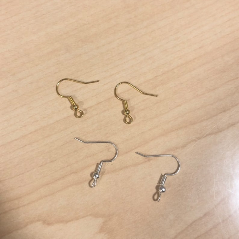 May include: Four earring hooks, two gold and two silver, with a small ball at the end of each hook.