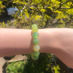 May include: A green and yellow gemstone bracelet with round beads. The bracelet is made of natural stones and is a beautiful accessory for any occasion.
