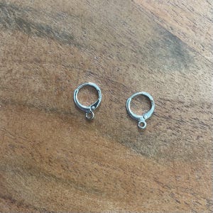 May include: Two silver hoop earring findings with a small loop at the bottom.