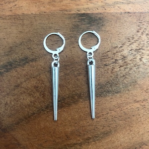 Può includere: Un paio di orecchini d'argento con un design a punta. Gli orecchini hanno una chiusura ad anello.