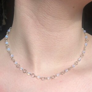 May include: A silver chain necklace with small, iridescent white beads.