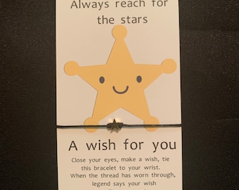 May include: A black string bracelet with a gold star charm. The card attached to the bracelet reads "Always reach for the stars. A wish for you. Close your eyes, make a wish, tie this bracelet to your wrist. When the thread has worn through, legend says your wish will come true!"