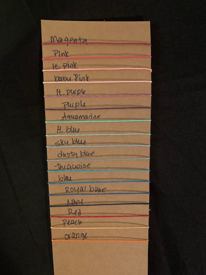 May include: A brown card with a list of colors and their corresponding string colors. The colors are: Magenta, Pink, It. Pink, baby Pink, H. Purple, Purple, Aquamarine, H. blue, Sky blue, dusty blue, thrquoise, blue, Royal blue, Navy, Red, Peach, orange.