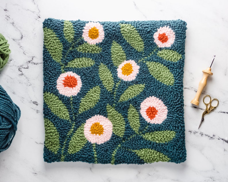 May include: A teal blue hand-stitched rug with a floral design. The rug features pink, orange, and yellow flowers with green leaves.