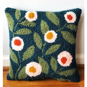 May include: A teal blue throw pillow with a floral pattern. The pillow features white, pink, orange, and yellow flowers with green leaves.