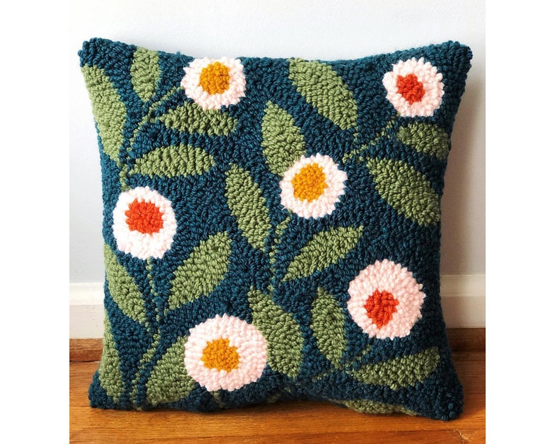 May include: A teal blue throw pillow with a floral pattern. The pillow features white, pink, orange, and yellow flowers with green leaves.