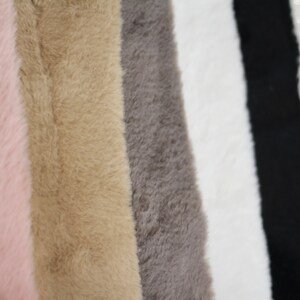 May include: Five fabric swatches in different colours: pink, beige, grey, white, and black. The fabric has a soft, fuzzy texture.