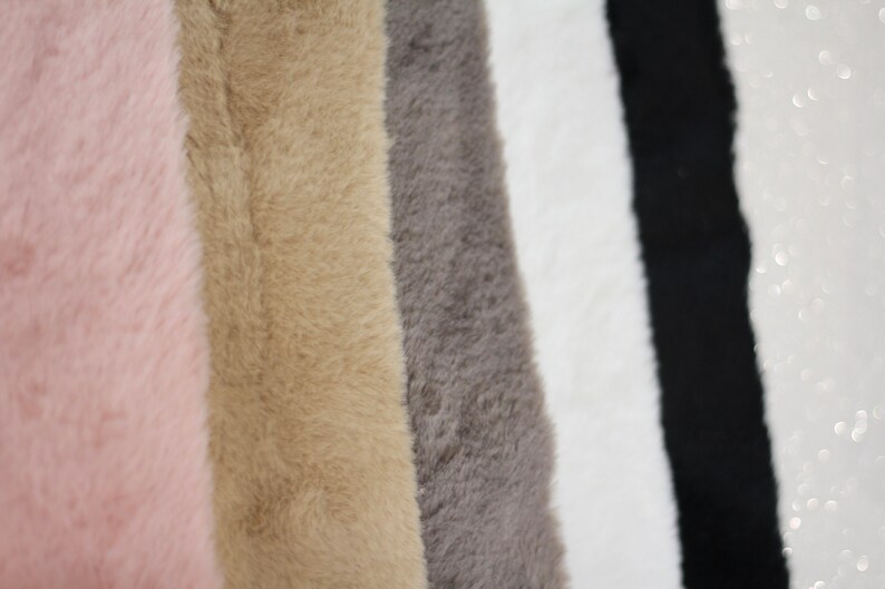 May include: Five fabric swatches in different colours: pink, beige, grey, white, and black. The fabric has a soft, fuzzy texture.